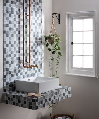 A bathroom with a decorative mosaic tile panel around the sink