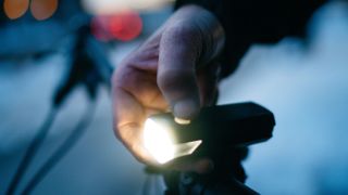 Person turning on front white bike light