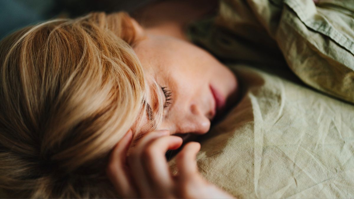 A woman sleeping with her hand on her head and a slight frown, showing she is thinking