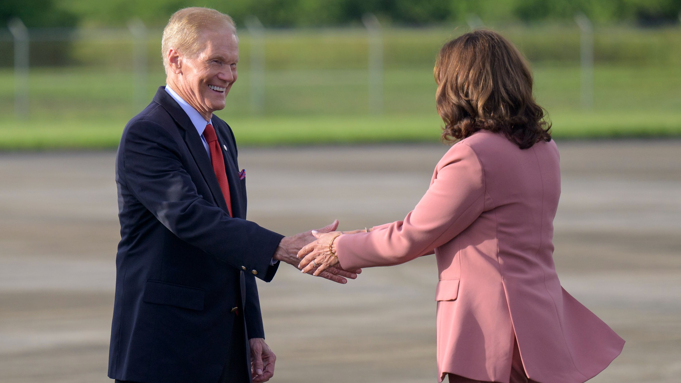 nasa administrator bill nelson in a suit shakes hands with vice president kamala harris in a pink blazer