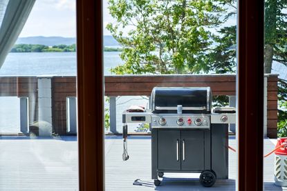 A gas grill on an outside decking with views of trees