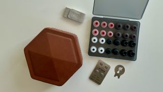 FiiO FH19 wired earbud accessories, including extra tips, red carry case, pins and stickers