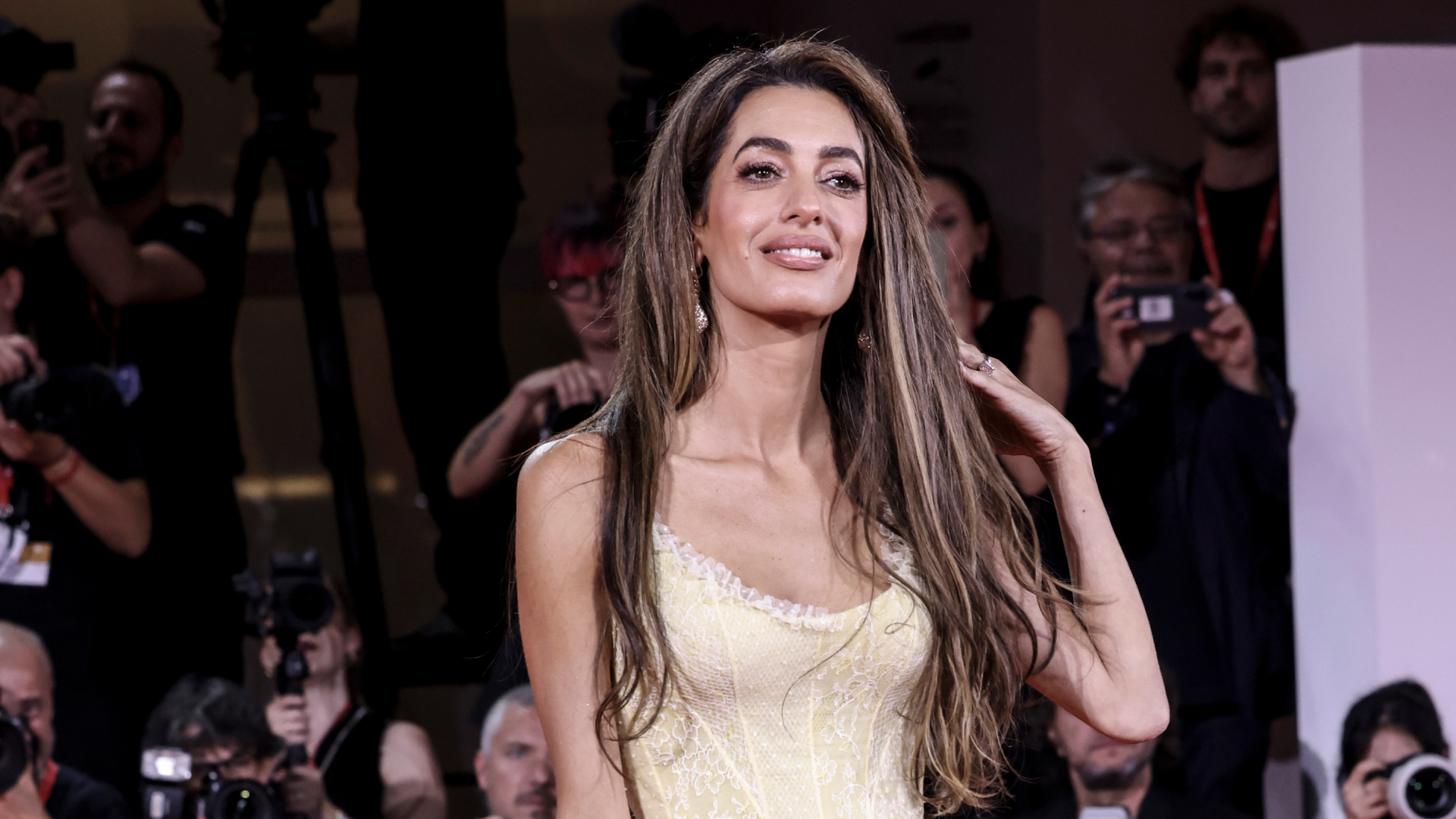 Amal Clooney wearing a yellow dress and posing on a red carpet