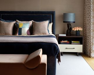 bedroom with brown wall, navy blue velvet headboard and patterned cushions