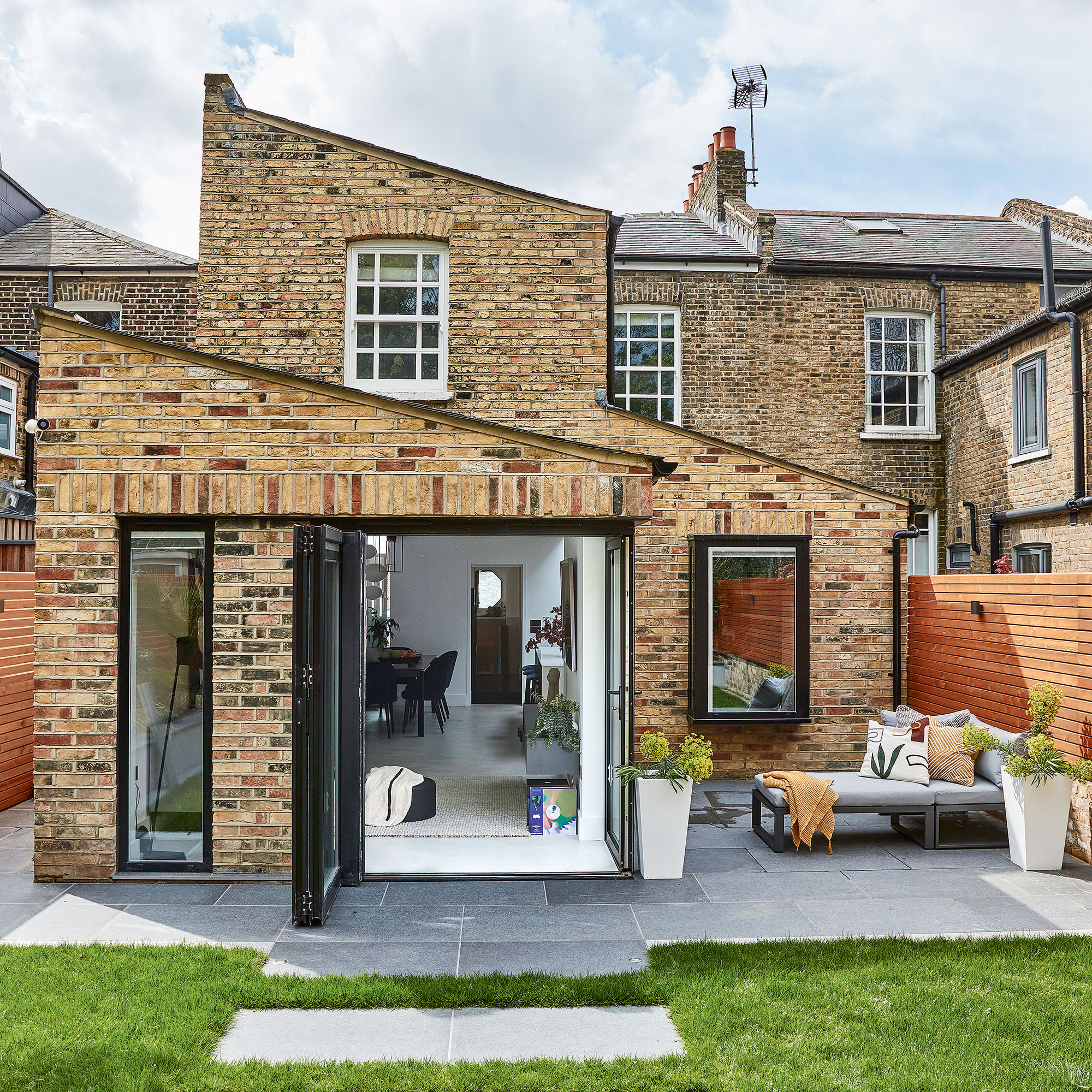 brick wall house exterior with white windows and garden