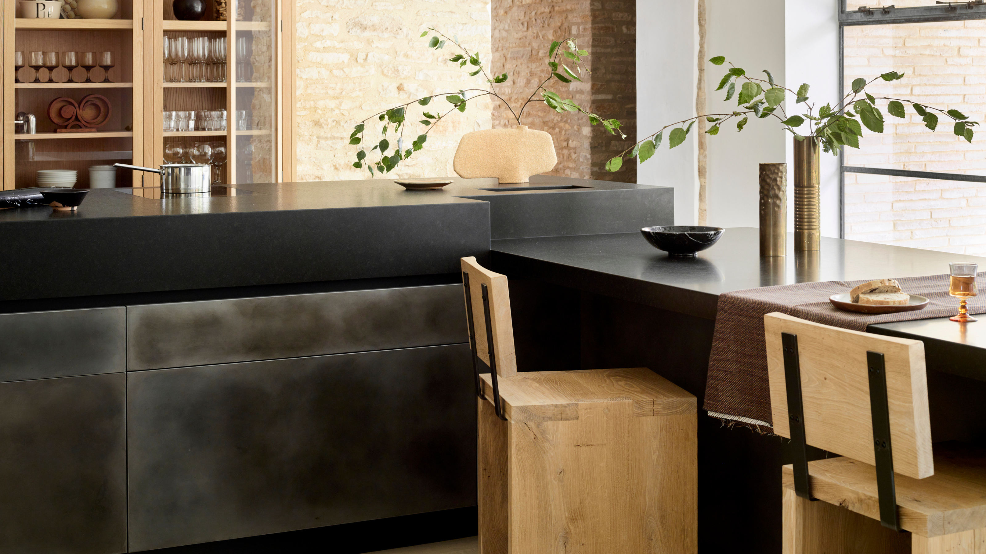 L shaped kitchen island with black counters and cabinets with soft light wood accents