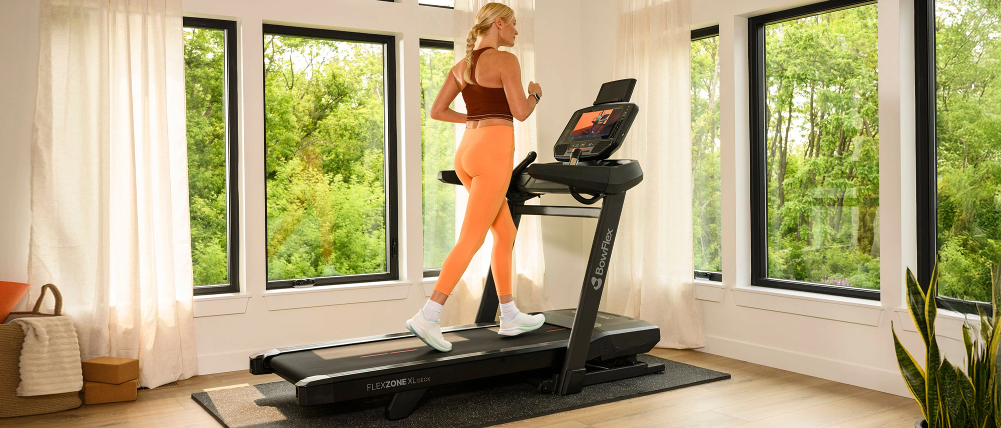 Woman running on the Bowflex T16 treadmill in spacious home 