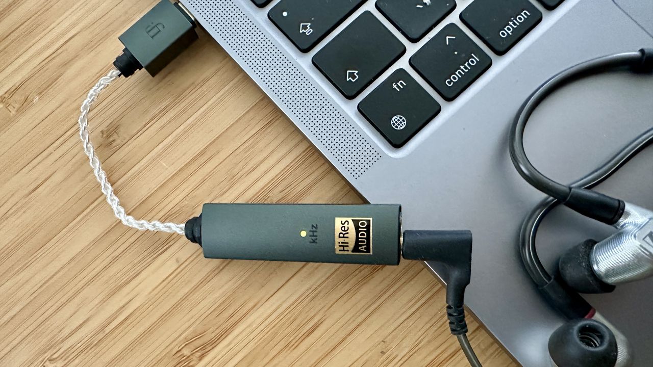 iFi Go Link Max on a wooden desk, plugged into Sennheiser iE900 in-ears and an Apple MacBook