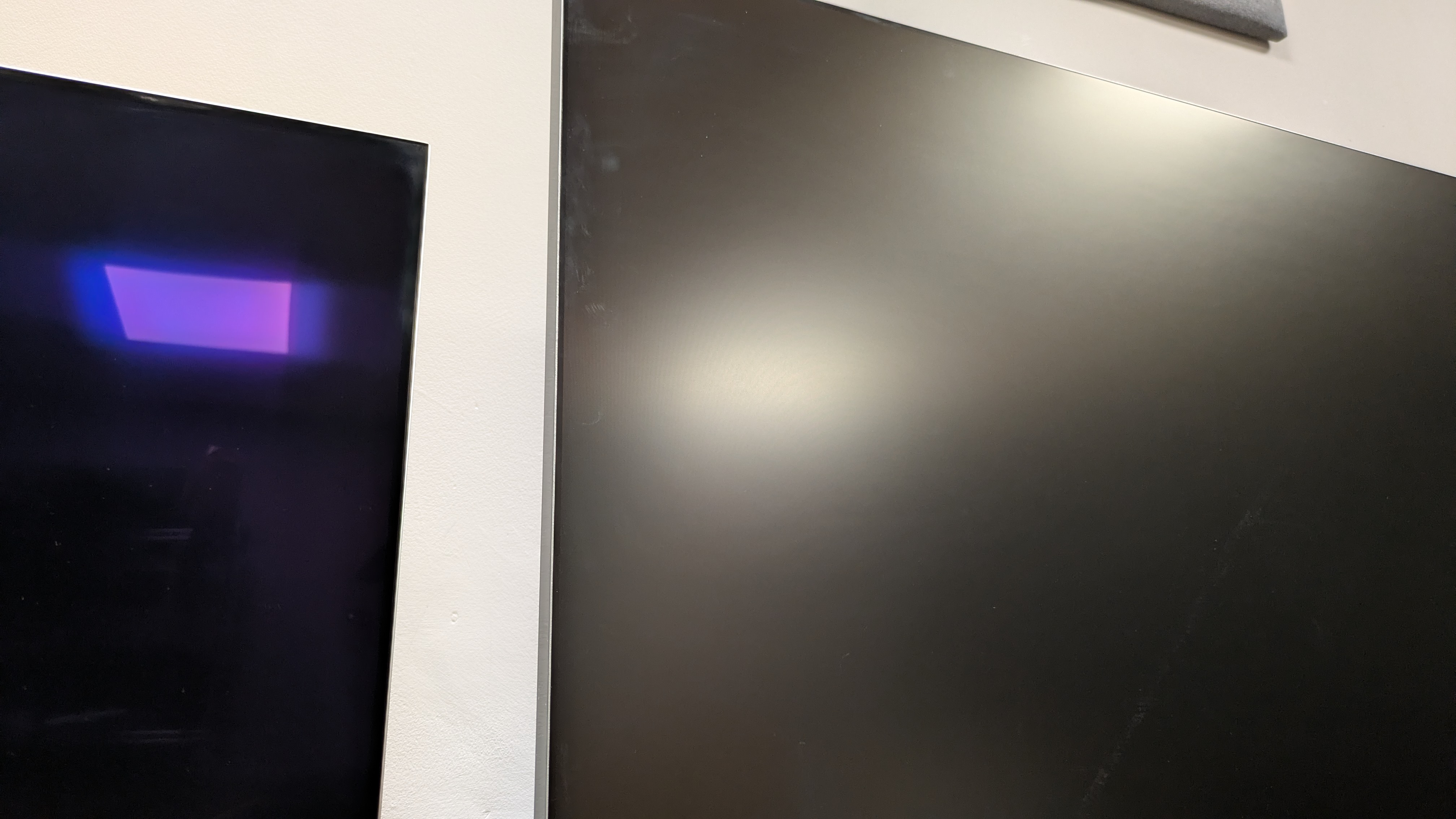 LG G6 (left) vs Samsung R95H (right) with overhead light reflected on screen. The R95H is the better TV for reducing mirror-like reflections
