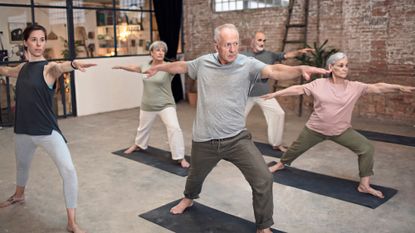 Group of seniors lunge forward in a yoga class