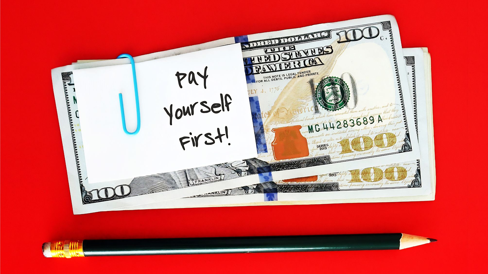 A stack of cash with a note paper clipped to it that says "Pay Yourself First!"