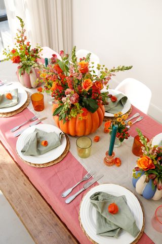 A Halloween themed tablescape with a pumpkin planter as a floral centerpiece
