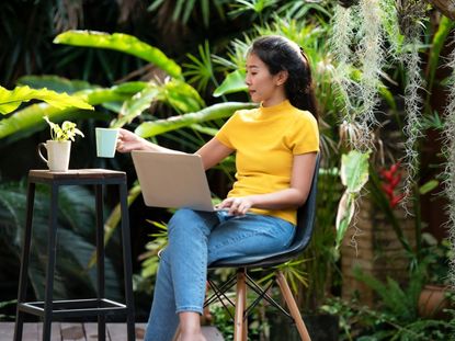 A Person Working On Her Laptop From A Garden Home Office