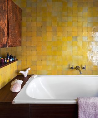 bathroom with bath with wooden surround, yellow zellige tiles and leather cupboard fronts