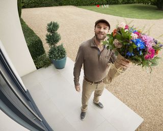 Courier at door with parcel and bouquet of flowers