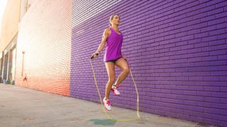 woman skipping outside infront of purple wall