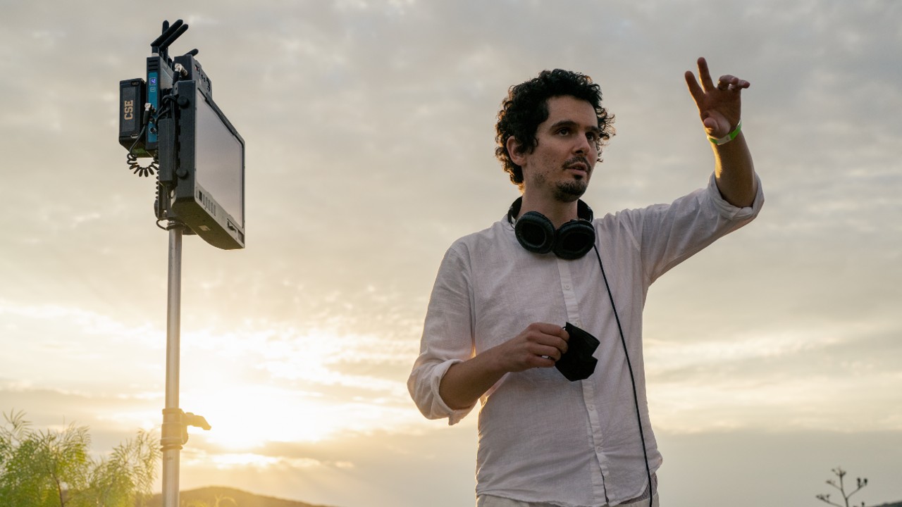 Damien Chazelle usando audífonos y dirigiendo en el set de Babylon.