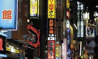 View along a row of illuminated shop signs in Tokyo at night