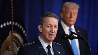 Gen. Dan Caine speaks with President Donald Trump in the background