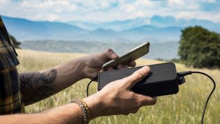 Man Using Portable Speaker Connected to Mobile Phone in Nature 