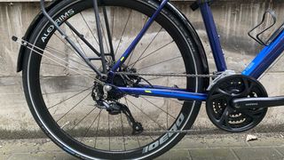 The rear end of a blue bike with triple chainset and pannier rack