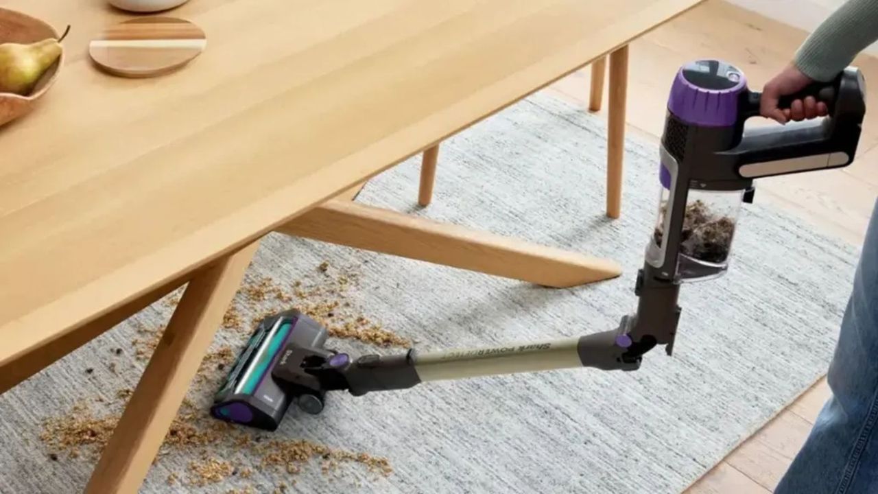 Cordless vacuum cleaning carpet under wooden table