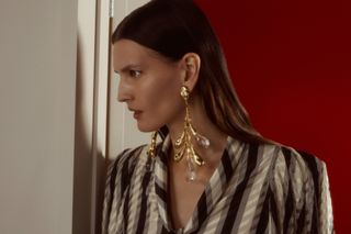 Model in colourful, eclectic outfit walks through a door to a red room wearing looks from the S/S 2025 season