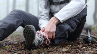 Hiker sitting on floor holding injured ankle