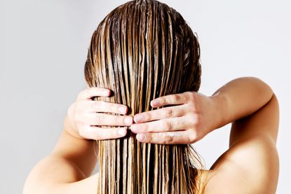 Blond woman applying hair conditioner. Isolated on white.