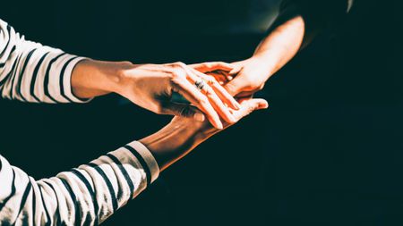 Two people holding each other's hands against a black background.