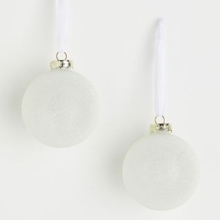 Two white ornaments from H&M on a white background