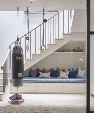 An under stairs idea with blue and white upholstered seating bench under white staircase