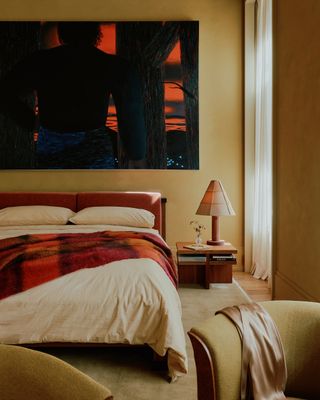 a pale yellow bedroom with large wall art and cream bedding