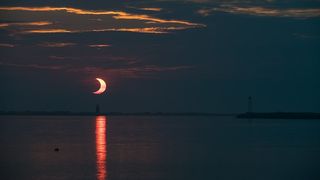 A view of the partially eclipsed sun rising over the Delaware Breakwater Lighthouse on June 10, 2021, by Aubrey Gemignani.