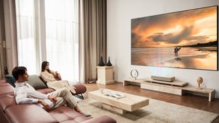 A couple watching the LG HU915QE in their living room.