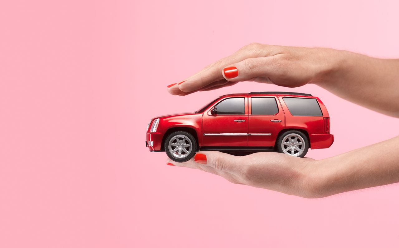 Image of a red car placed between someone&#039;s hands.