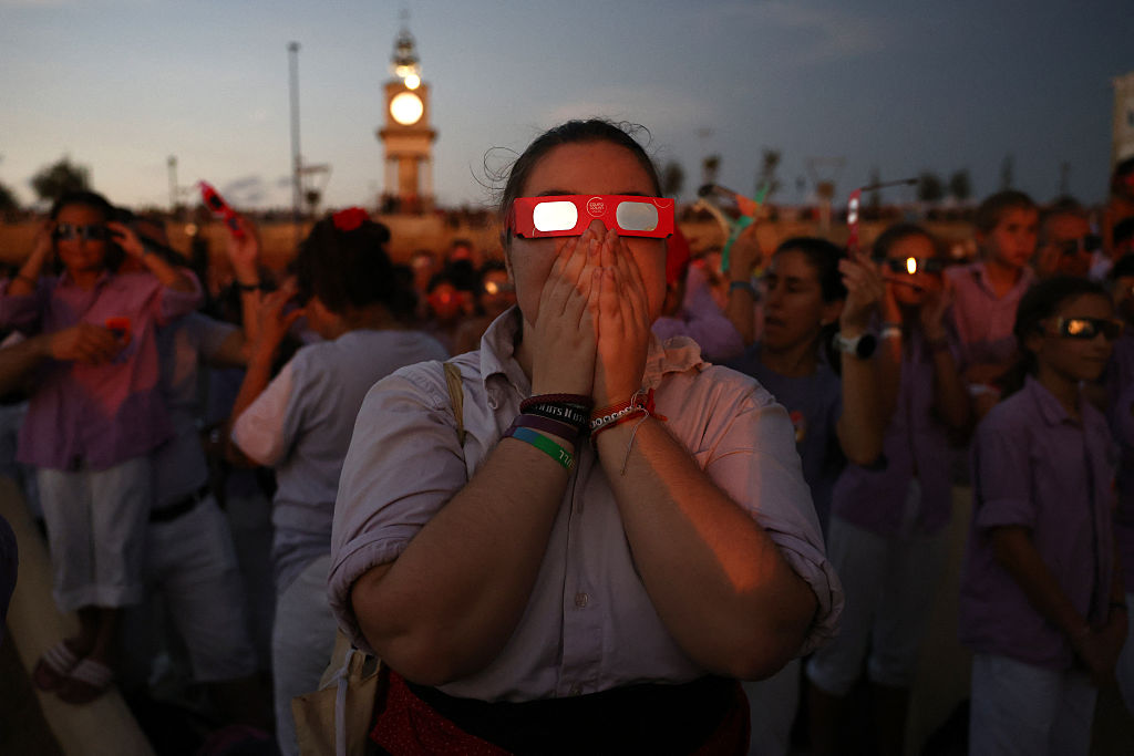People react as they observe the total solar eclipse from the sea port of Tarragona, northeastern Spain, on August 12, 2026. (Photo by Josep LAGO / AFP)