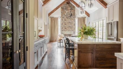 An open plan kitchen and living space with warm white cabinets and a wood island filled with a mix of drawers and cabinets for mazimum storage