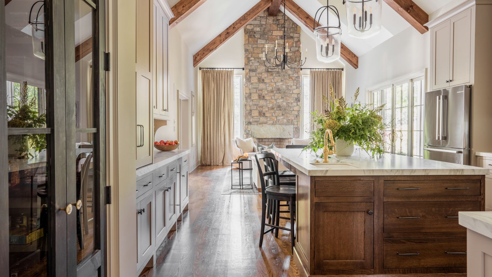 An open plan kitchen and living space with warm white cabinets and a wood island filled with a mix of drawers and cabinets for mazimum storage
