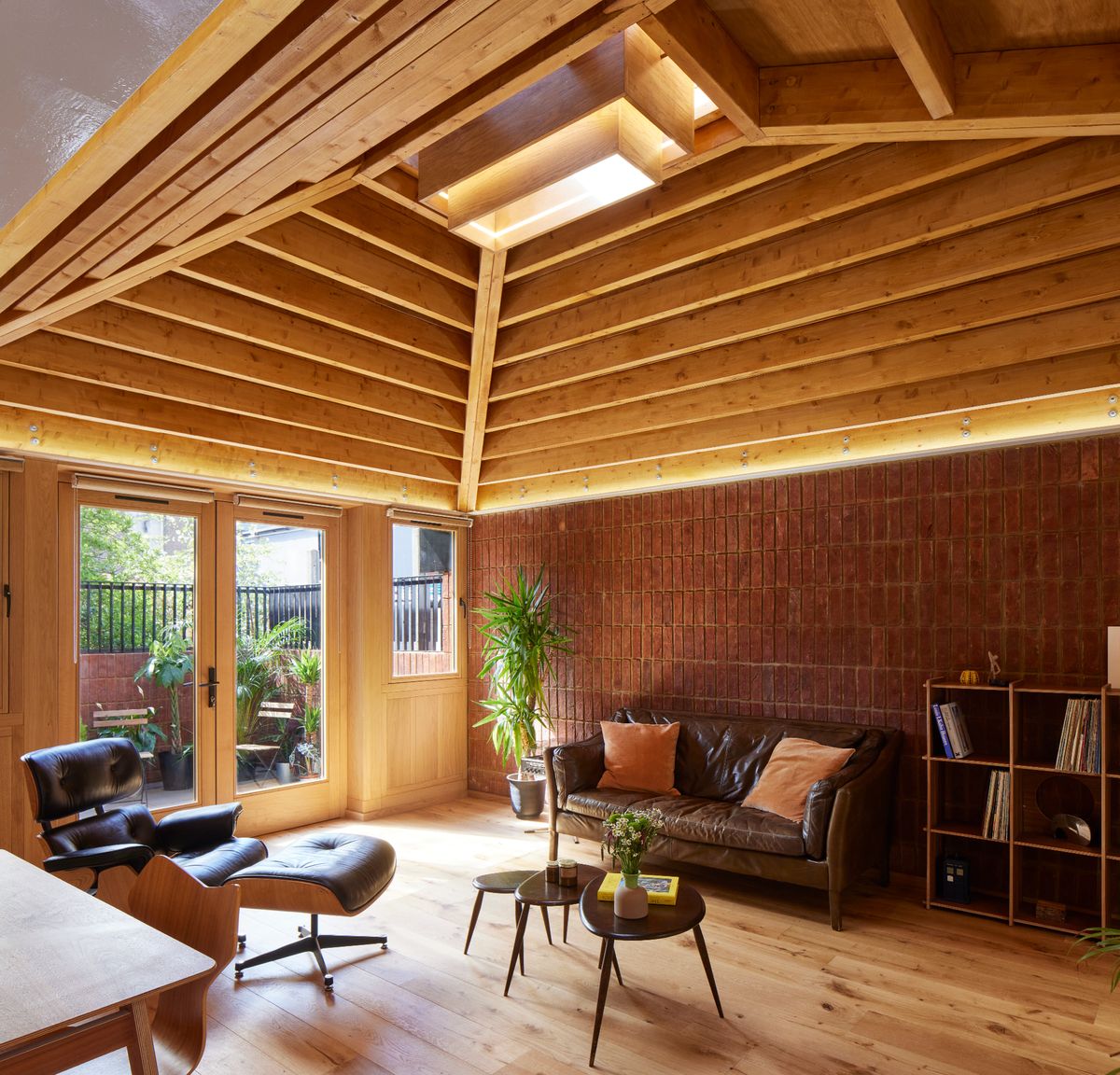Interior of a bungalow with an exposed brick wall, midcentury furniture and a vaulted ceiling with skylight
