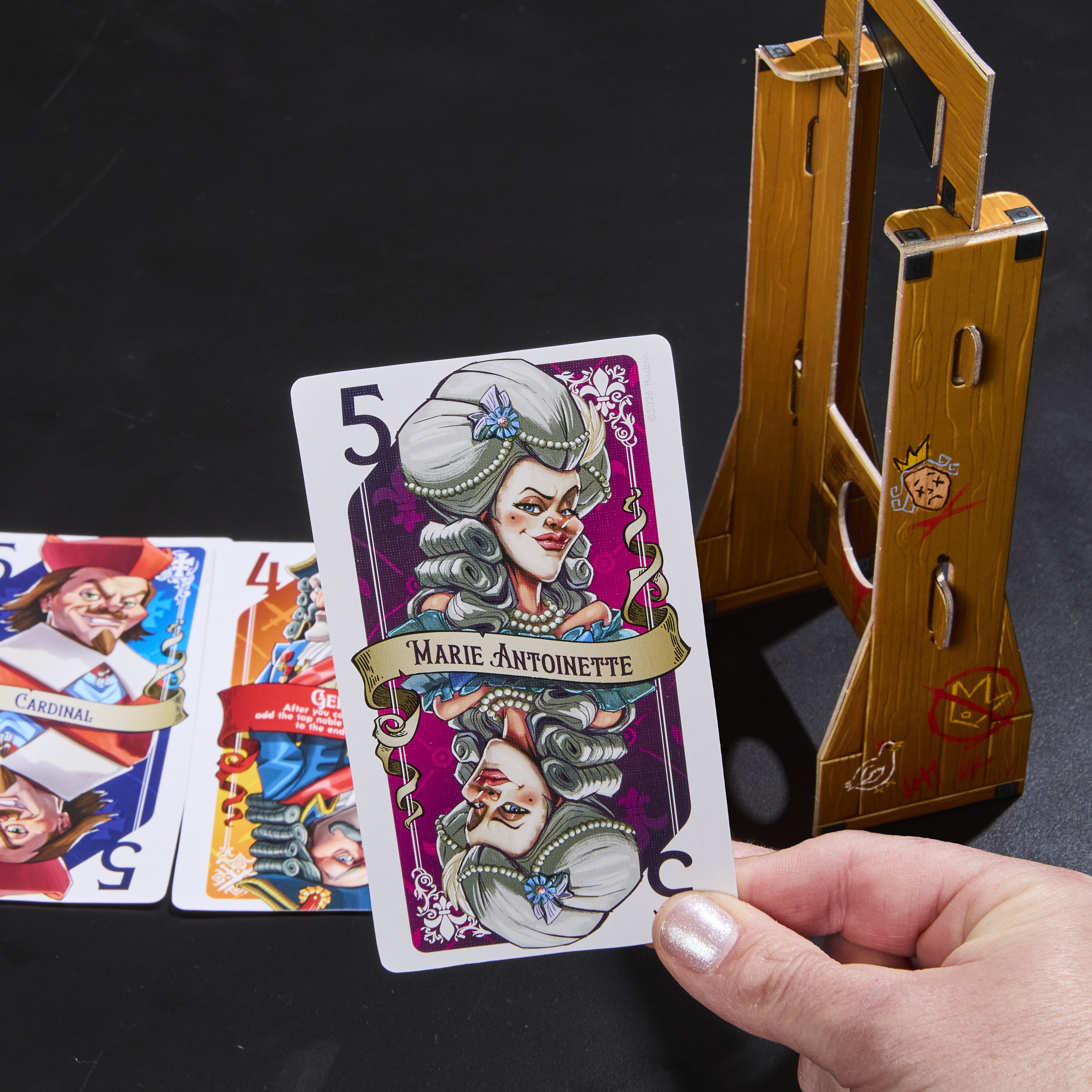 Guillotine box, cards, and prop on a dark background