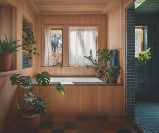 bathroom with lots of wood panelling including bath surround and blue tiled walk-in shower