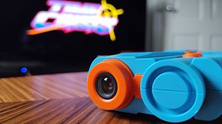 Close up of G'AIM'E Time Crisis Lightgun AI-powered camera lens on woodgrain table.