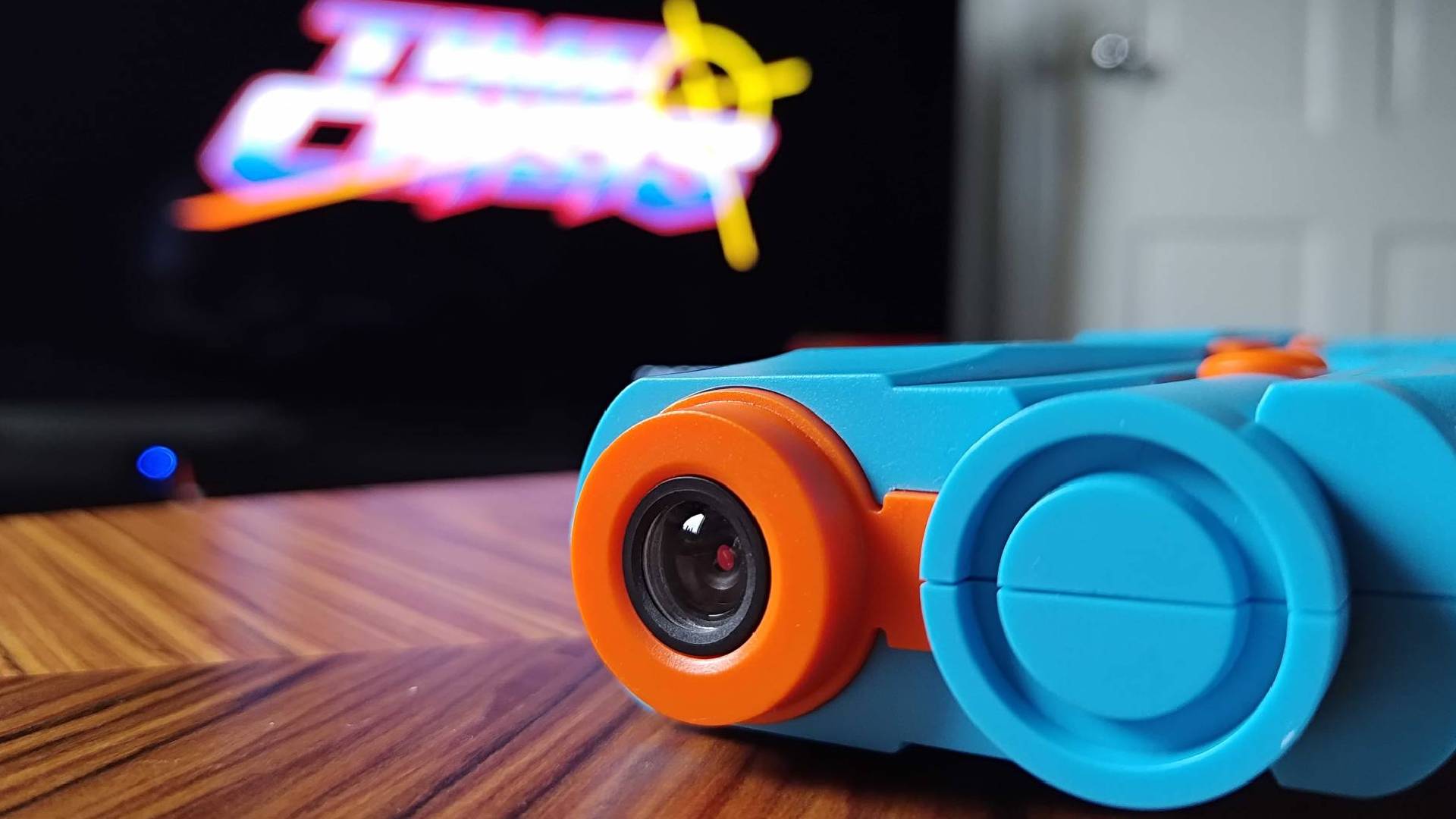 Close up of G'AIM'E Time Crisis Lightgun AI-powered camera lens on woodgrain table.