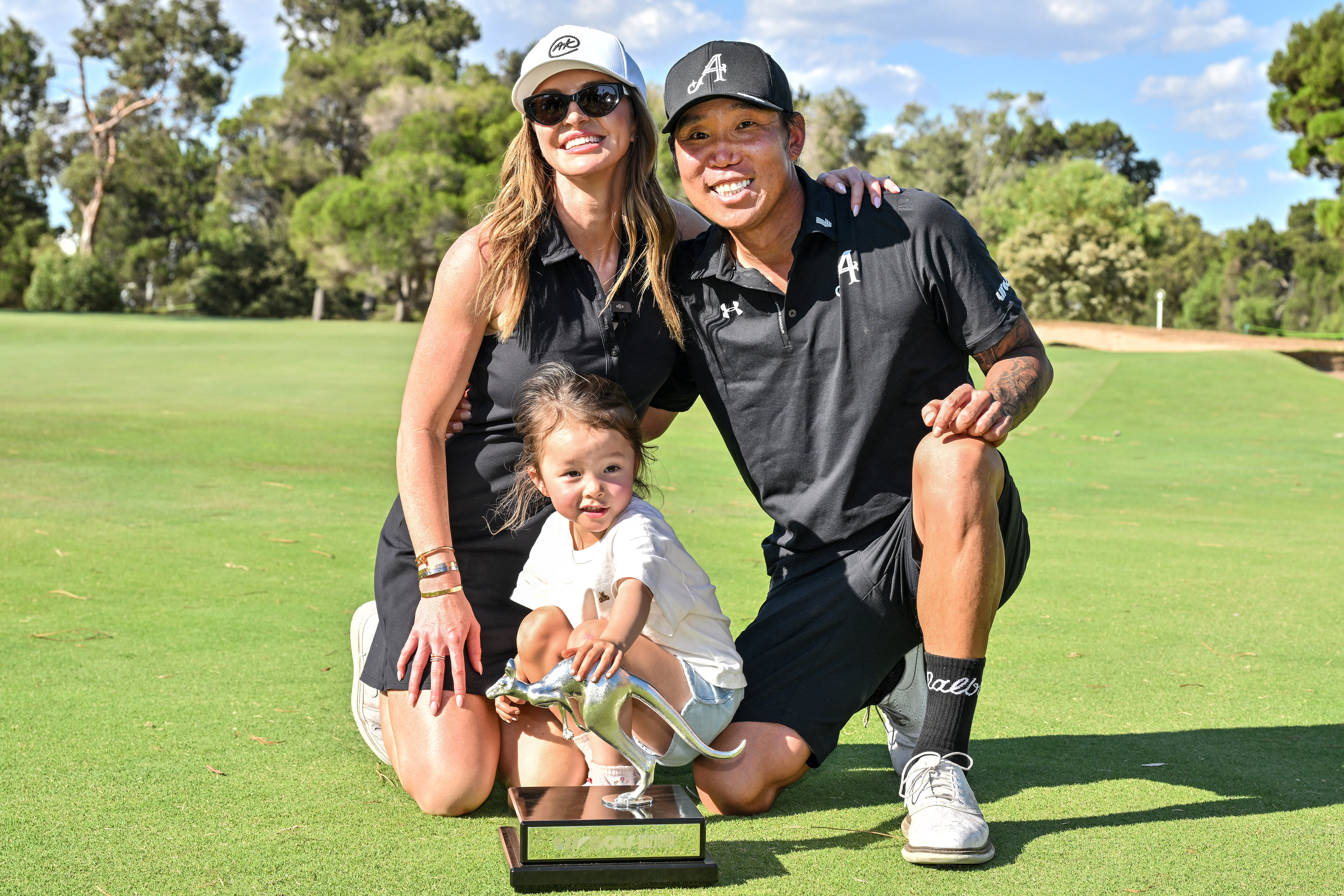 Anthony Kim poses with the LIV Golf Adelaide trophy and his wife Emily and daughter Bella
