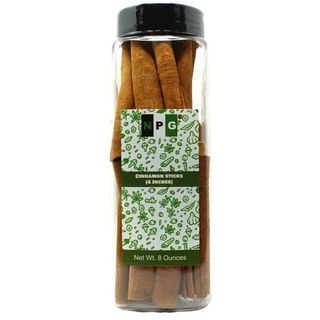 Vertical cylindrical plastic see-through jar with black lid showing vertically stacked cinnamon sticks 