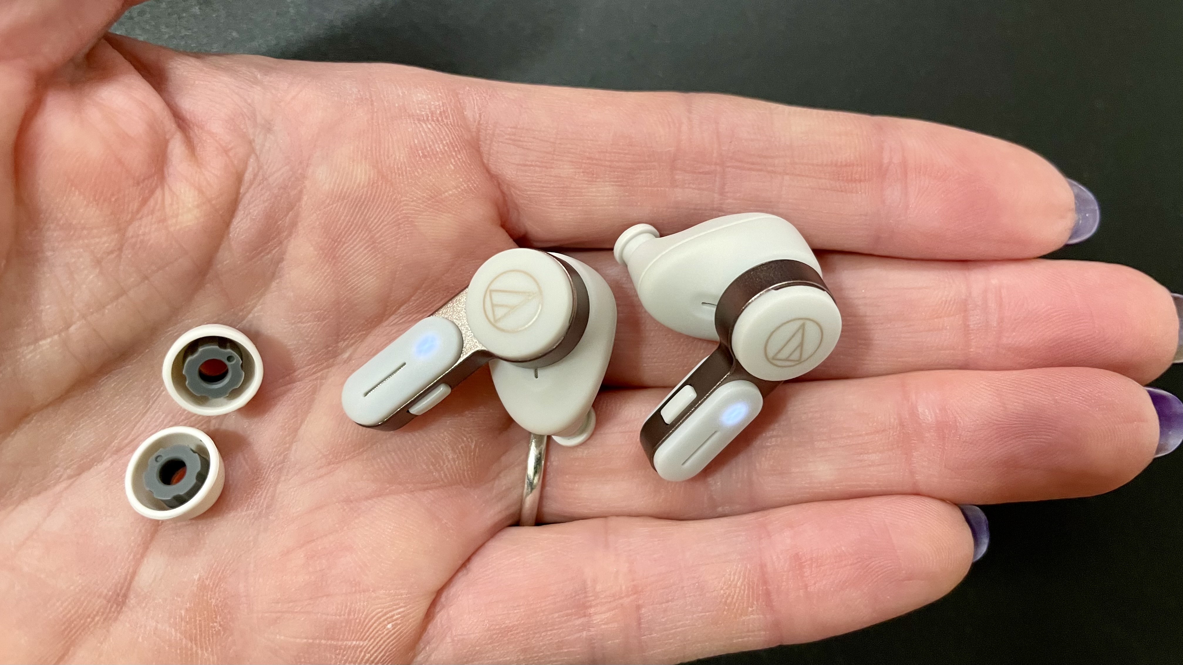 Audio-Technica ATH-TWX7 held in a hand, with earbud tips displayed