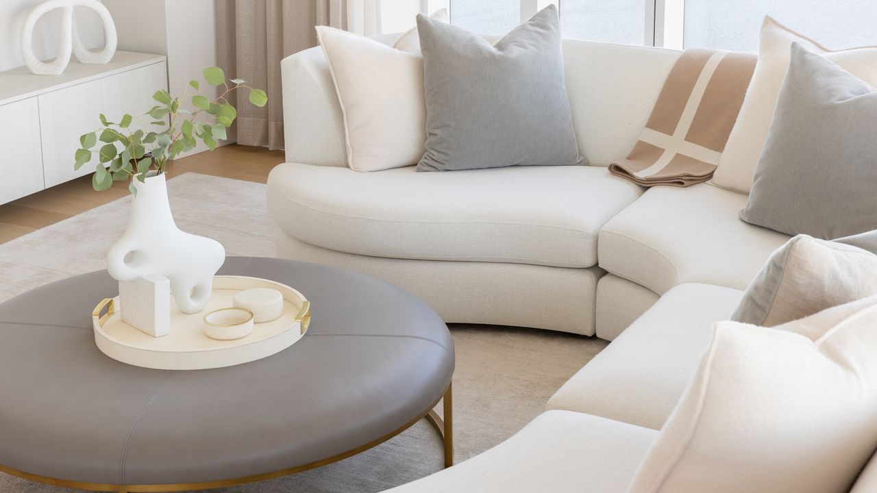 Living room with neutral sofa and pillows and leather upholstered coffee table