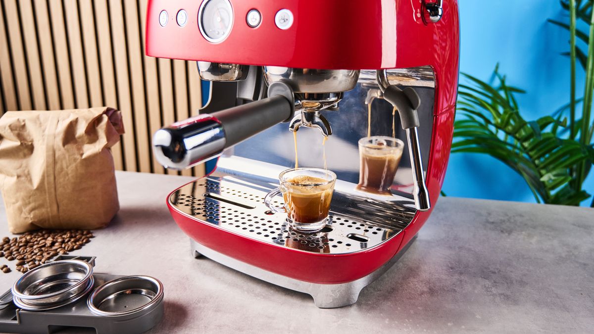 a red smeg espresso machine with burr grinder is photographed against a blue background