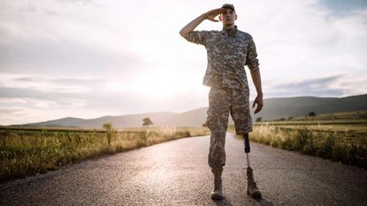 A soldier with a prosthetic leg salutes.